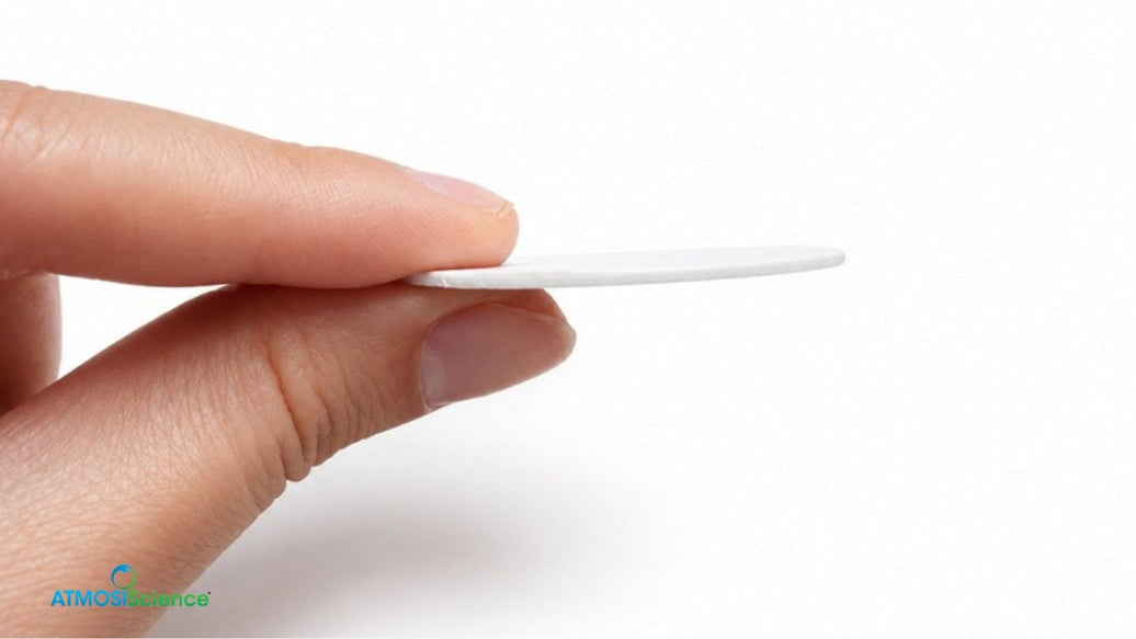 A thin round Fiber Desiccant Card held between two fingers