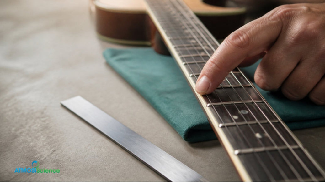 Hand feeling fret ends along an acoustic guitar neck, checking for dry guitar symptoms