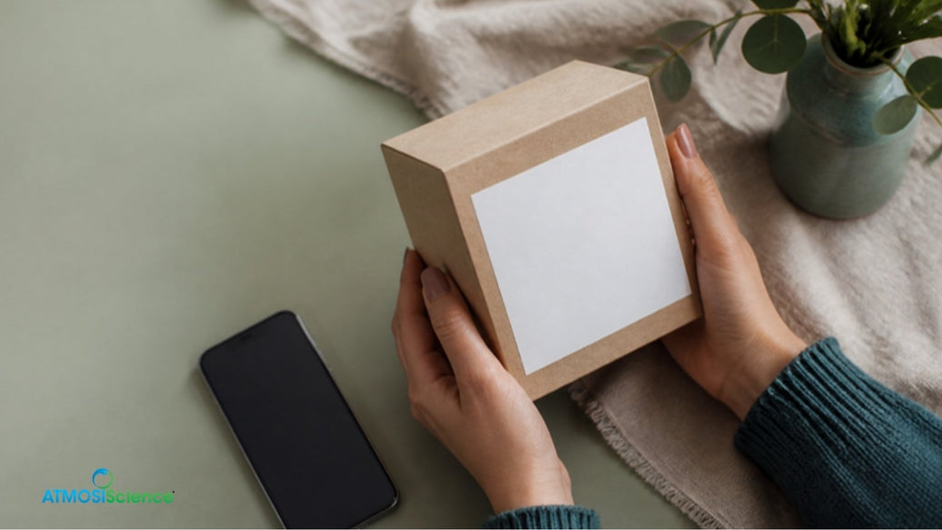 Hands turning a blank kraft product box to show the label panel for PPWR labelling